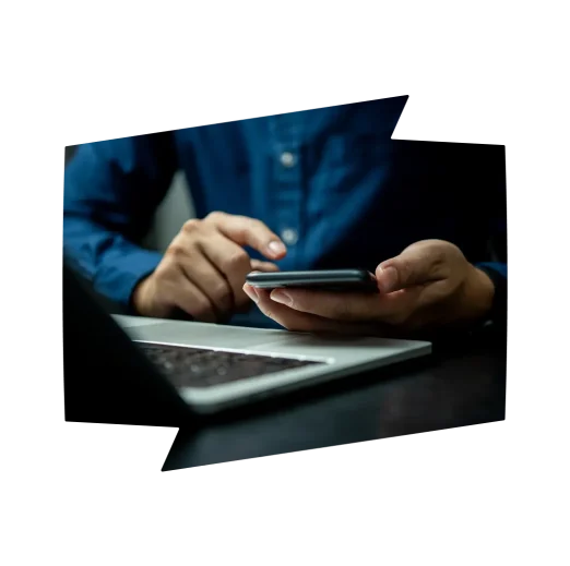 A man is using a cell phone while sitting at a desk