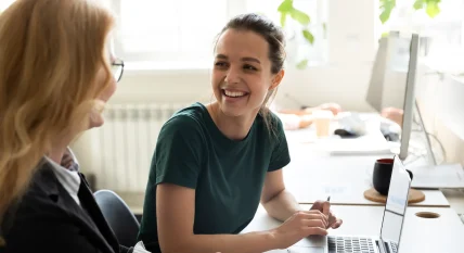 Happy smiling female trainee discussing business ideas with adult trainer
