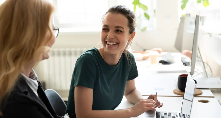 Happy smiling female trainee discussing business ideas with adult trainer