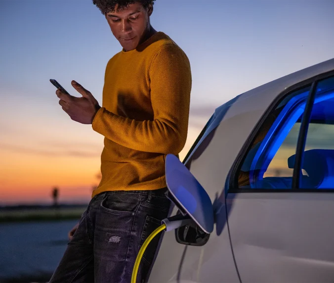 Man using mobile phone while charging electric car