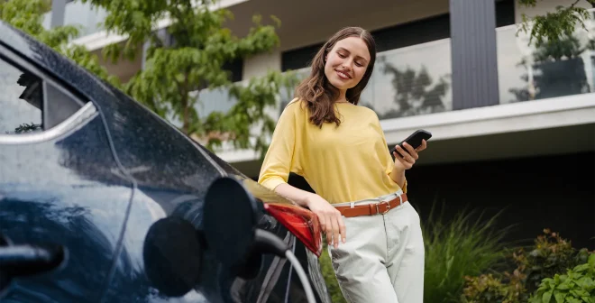 Smiling woman plugging charger in her electric car