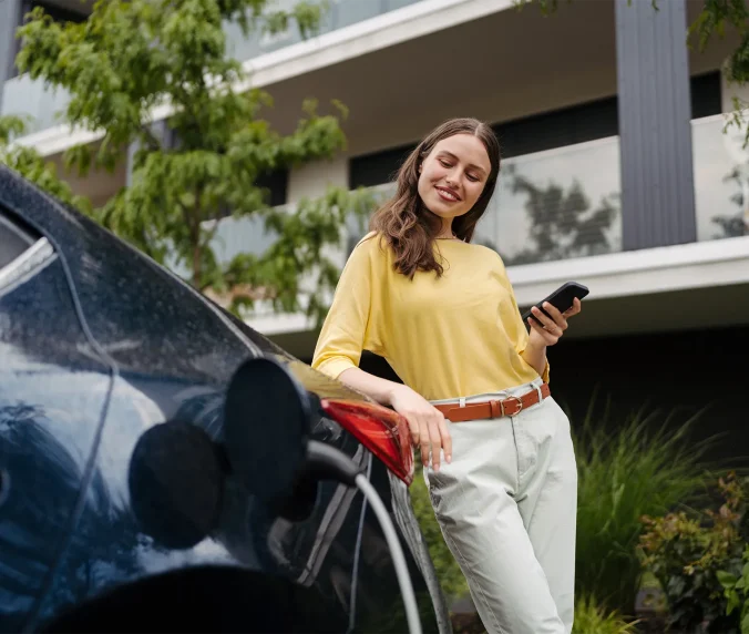 Smiling woman plugging charger in her electric car