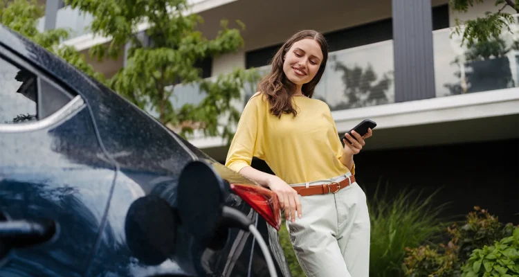Smiling woman plugging charger in her electric car