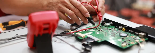 Cropped image of a mid-adult male Asian engineer measuring voltage on a conductor board in his workshop
