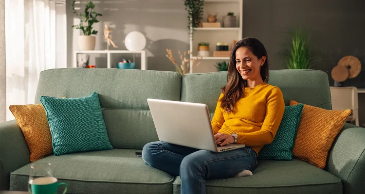 Portrait of a woman using laptop while sitting on a mint couch at home