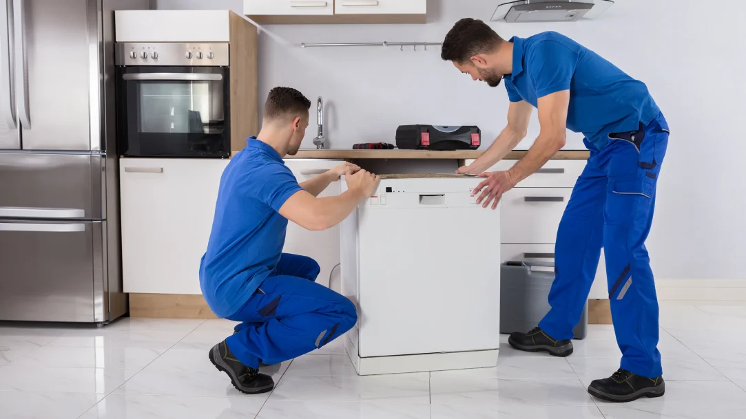 Two Movers Placing Dishwasher In Kitchen