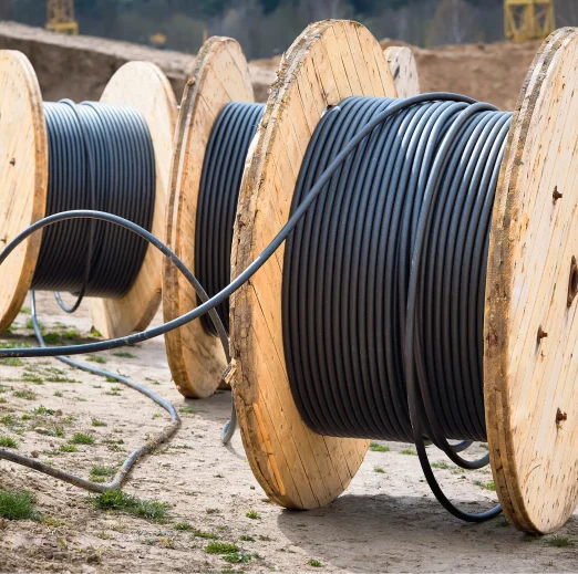 Concept of electricity supply for construction projects. Several wooden coils with power cable laid in trench