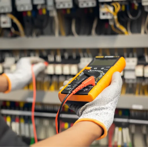 Electrician engineer uses a multimeter to test the electrical installation and power line current in an electrical system control cabinet